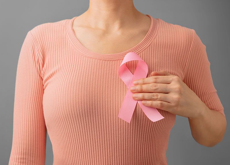 Mulher segura fita do Outubro Rosa para conscientização do câncer de mama